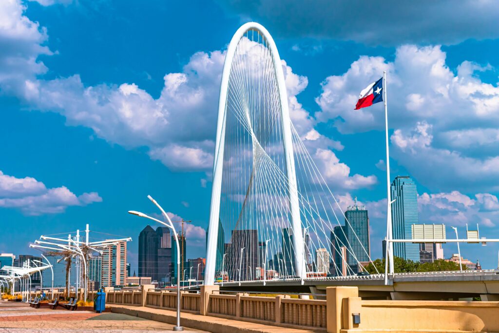 The iconic Margaret Hunt Hill Bridge in Dallas, Texas under a bright blue sky with clouds.