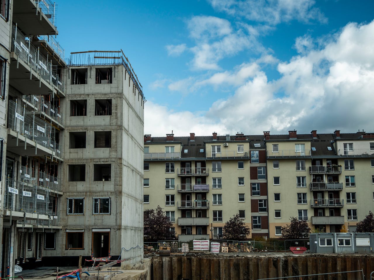 Construction site beside residential buildings under blue skies.