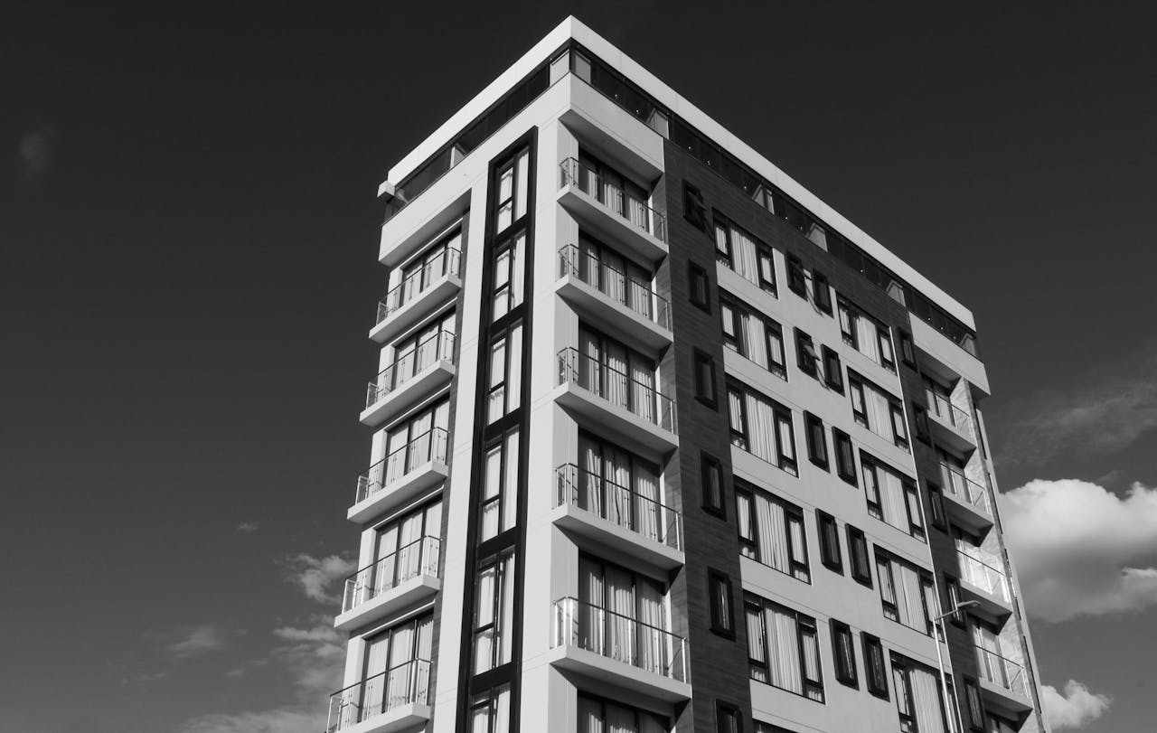 Black and white photo of a modern apartment building against a clear sky.