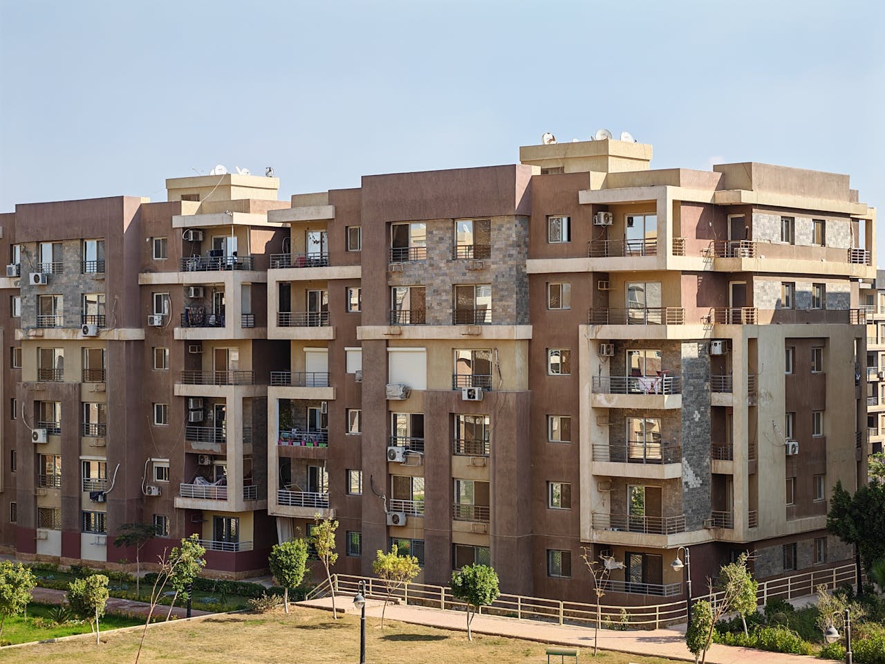 Contemporary multi-story apartment building with balconies in a sunny urban setting.