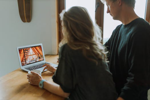 A couple viewing home interior design on a laptop while enjoying coffee together indoors.